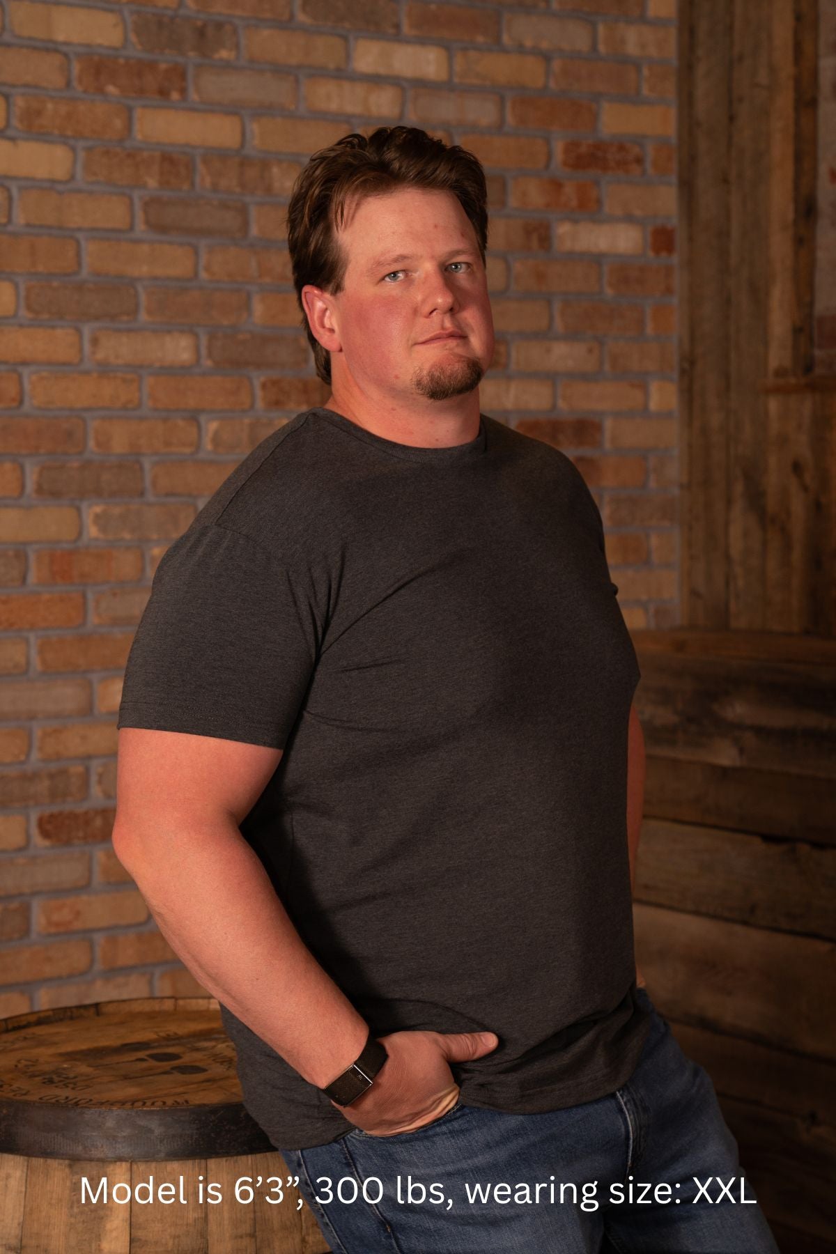 6'3", 300 pound man wearing a XXL dark gray t-shirt and jeans against a brick wall.