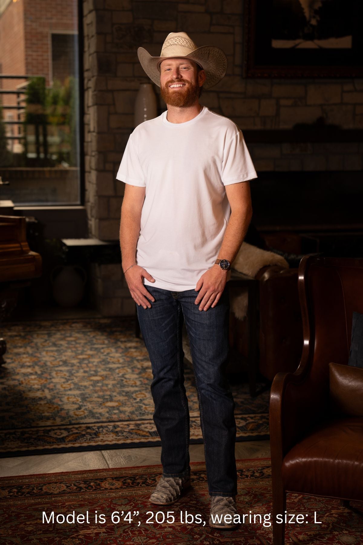 6'4", 205 pound man wearing a cowboy hat and size Large white t-shirt standing in a room with a fireplace.