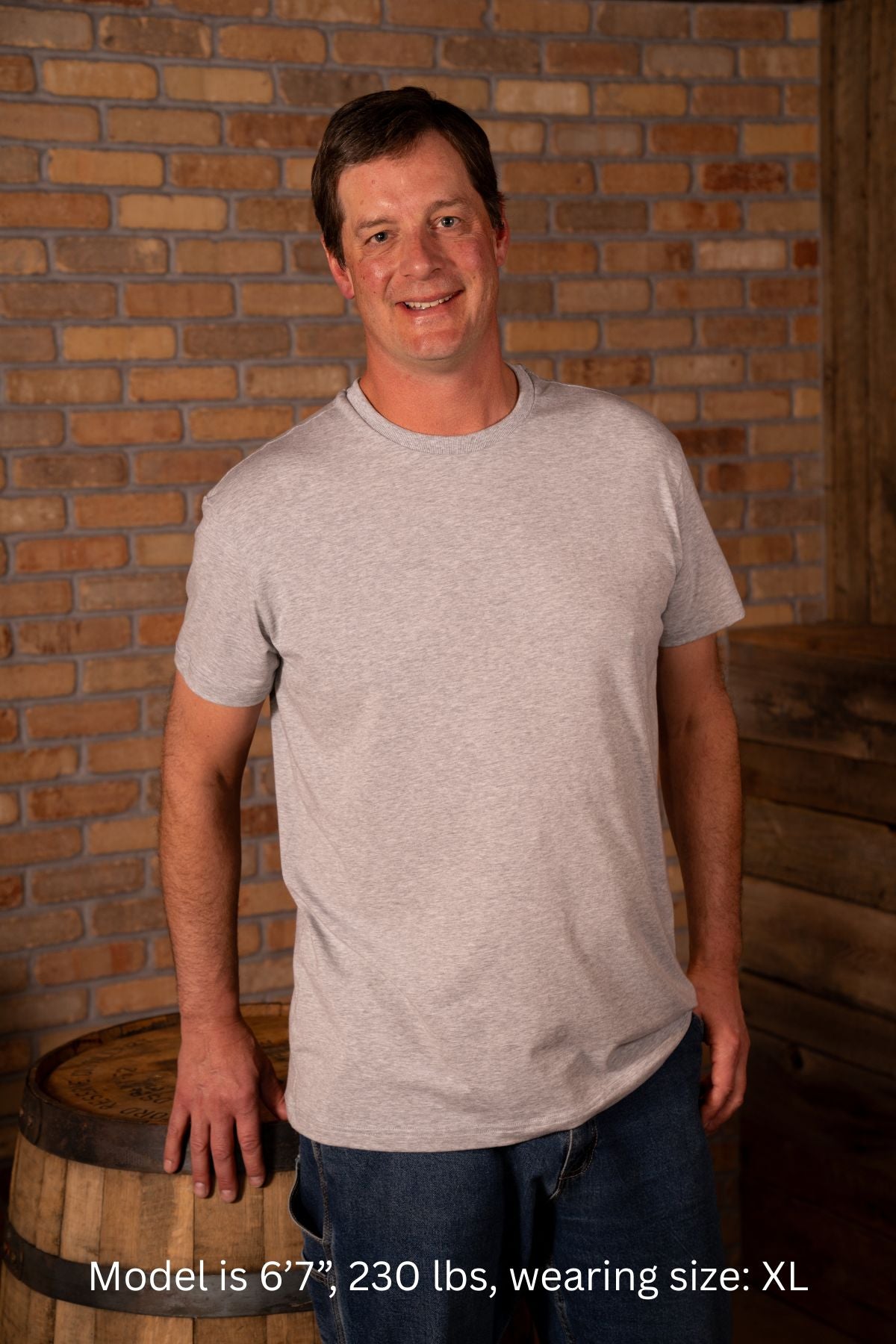 6'7", 230 pound man wearing a gray XL t-shirt standing in front of a brick wall.