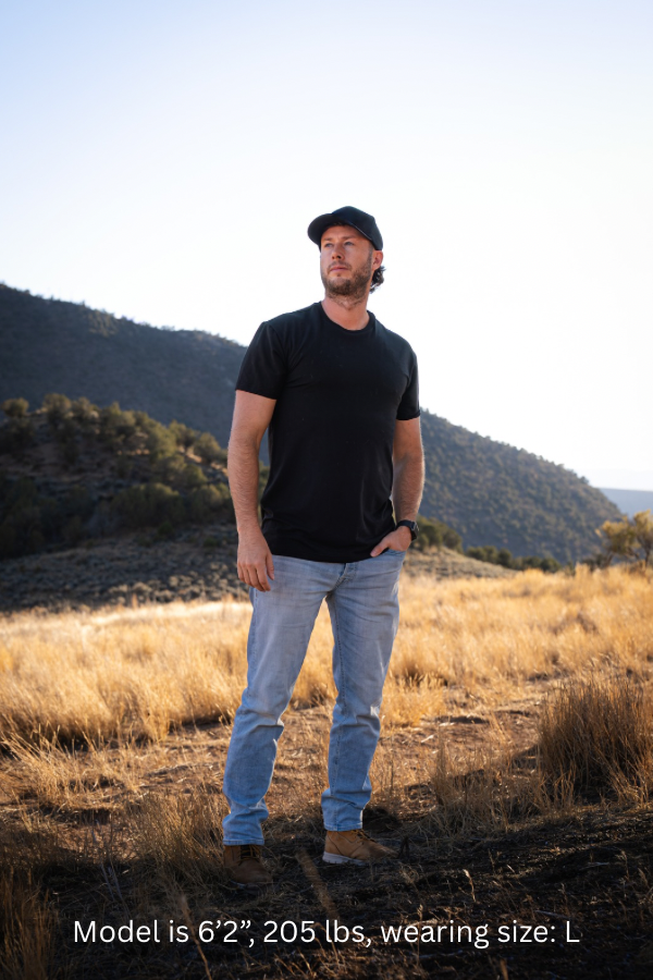 6'2" - 205# Man wearing a black colored shirt standing in a field with mountains in the background