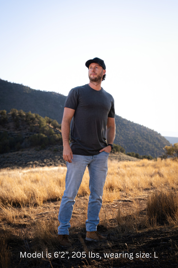 6'2" - 205#  Man wearing a charcoal mix colored shirt standing in a field with mountains in the background