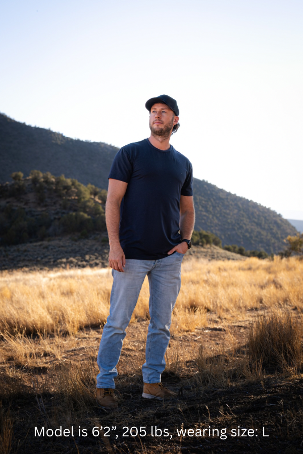 6'2" - 205#  Man wearing a navy colored shirt standing in a field with mountains in the background