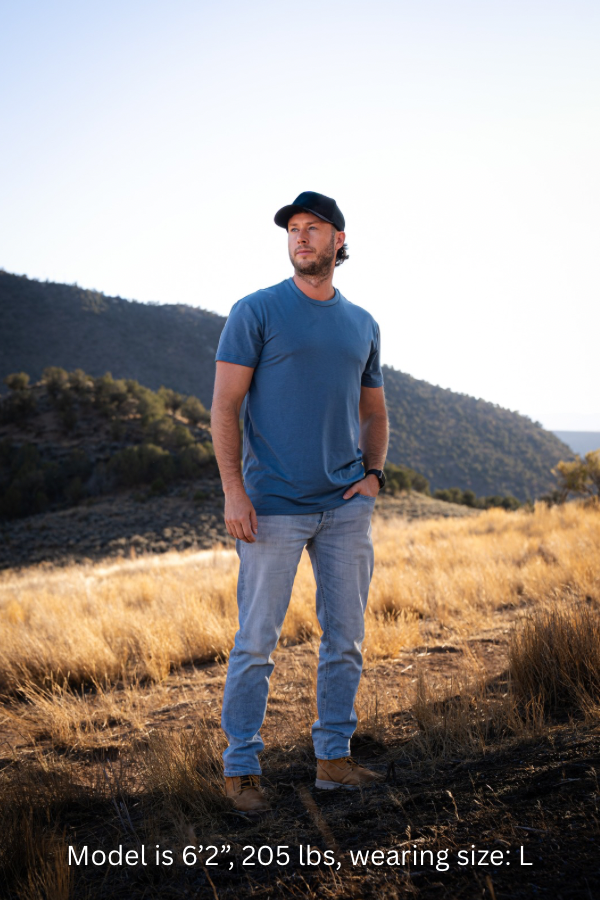 6'2" - 205#  Man wearing a stellar blue colored shirt standing in a field with mountains in the background