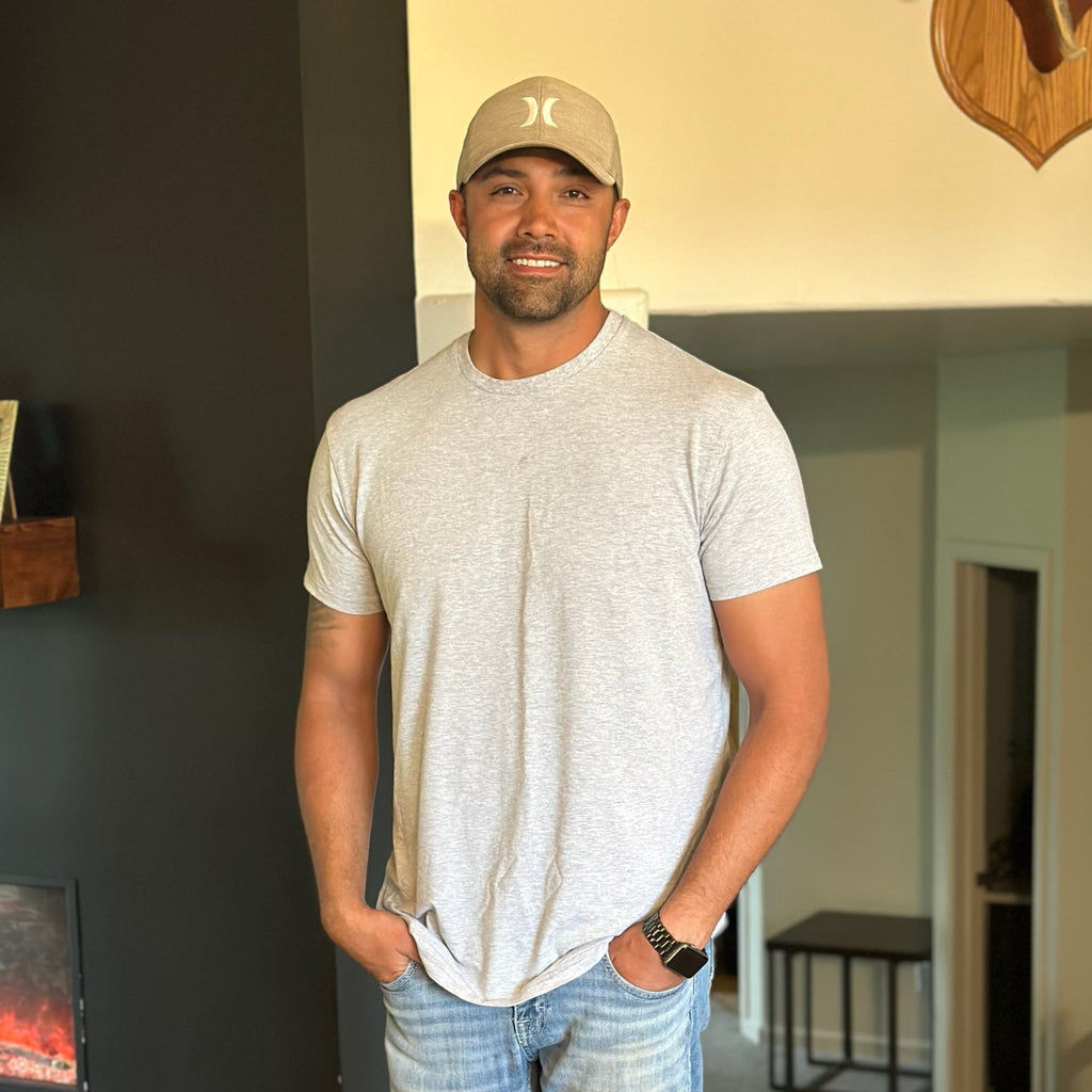 Man wearing a gray t-shirt and cap indoors
