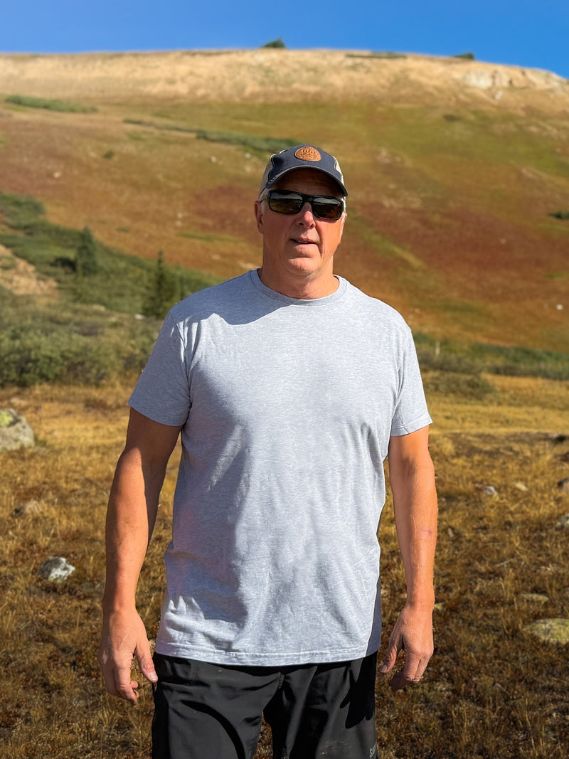 Man standing in a field with hills and blue sky in the background